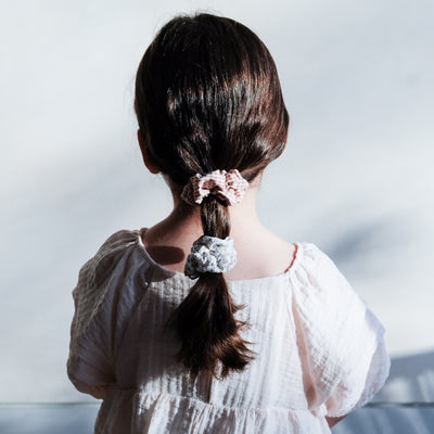 Soft pink gingham and earth tone floral scrunchies, worn in low ponytail by dark-haired little girl