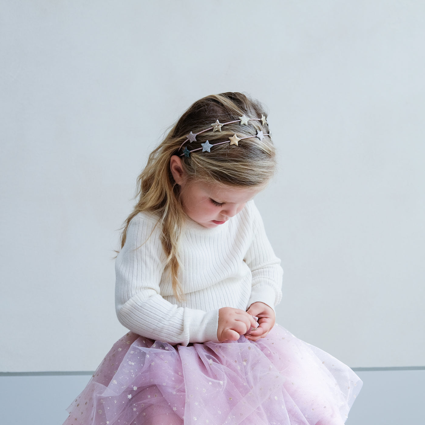 Little girl wearing a pink tutu and a sparkly star double Alice band