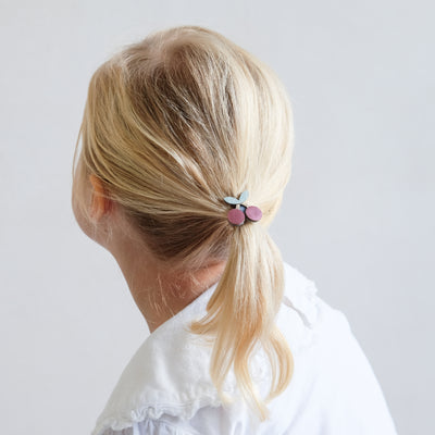 Little fine-haired girl with hair drawn back and tied with cherry pony, featuring metallic and glitter fabrics