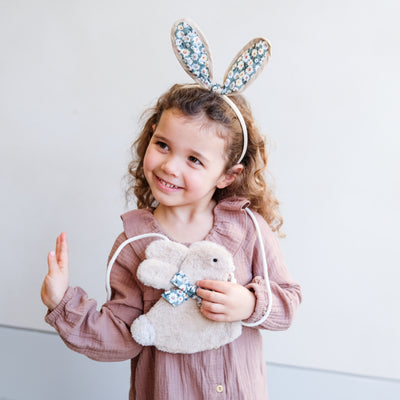 Little girl wearing floral bunny rabbit ears and holding a bunny bag