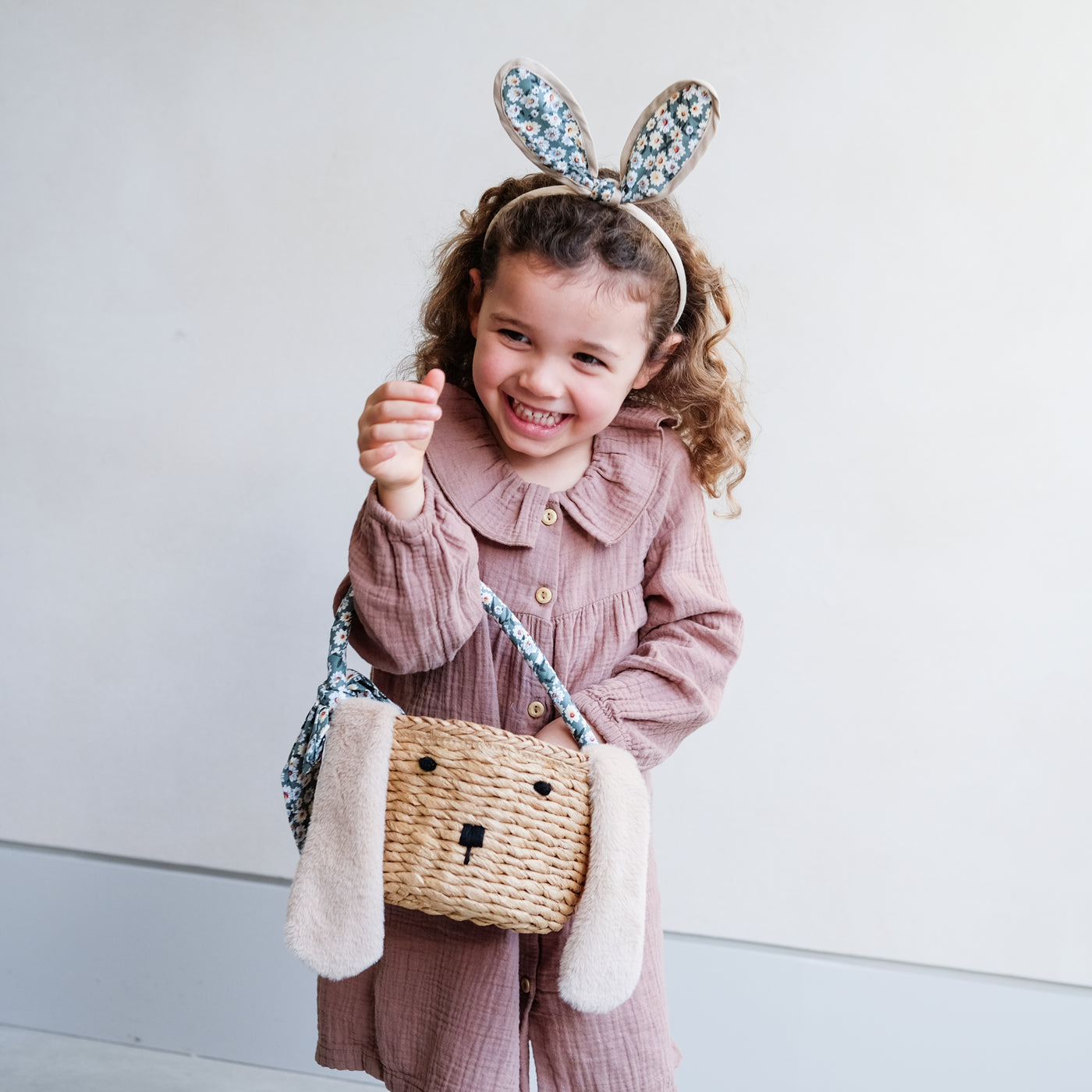 little girl with daisy print bunny ears headband holding Easter bunny basket