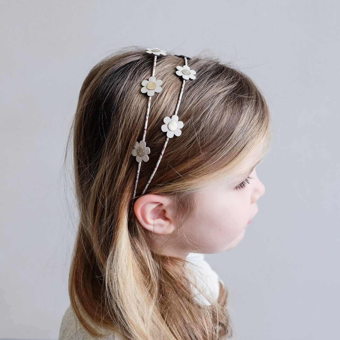Little girl wearing floral Alice band with daisies