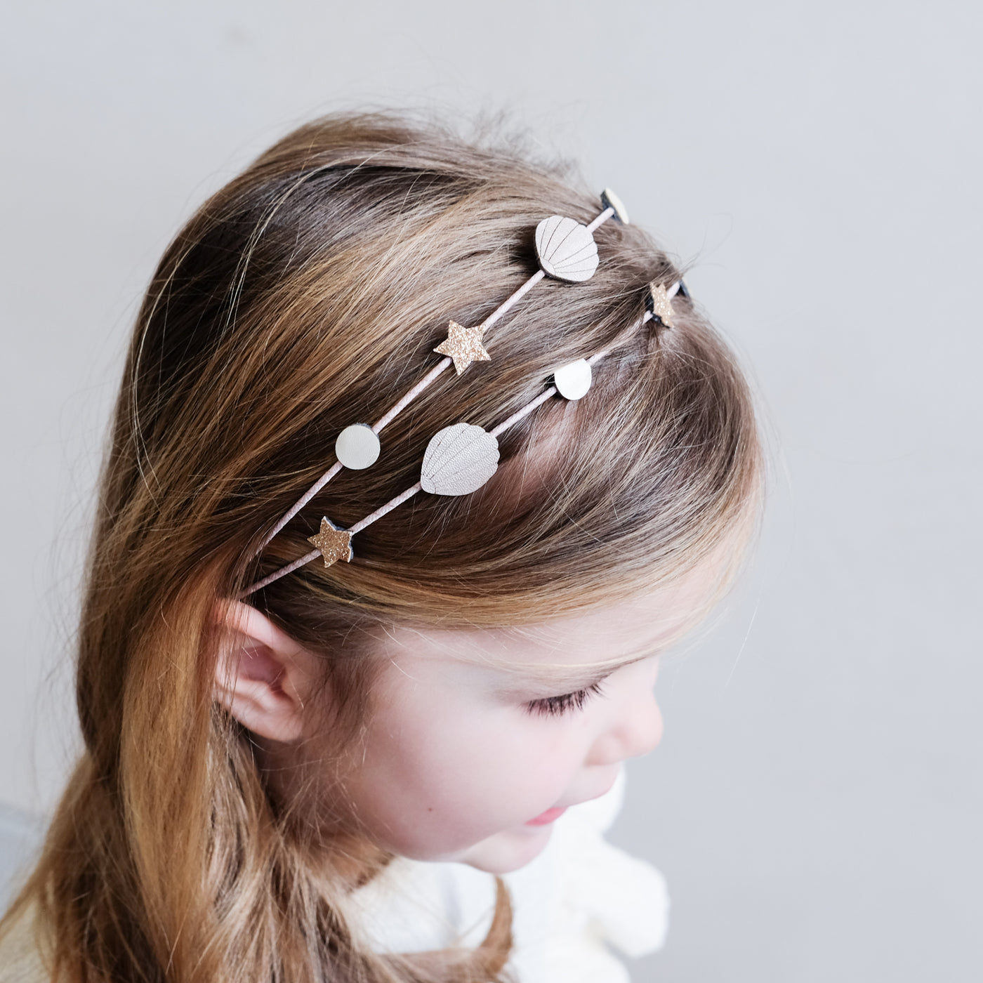 Little girl wearing a seaside theme double Alice band with stars, seashells and pearls
