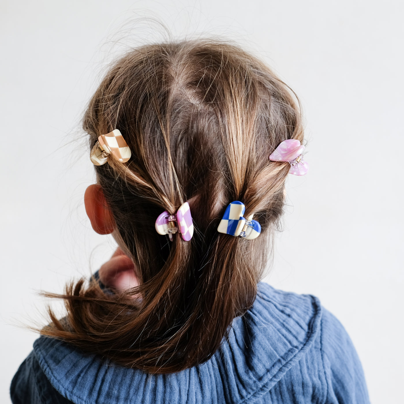 Close up image of a little girl wearing four different coloured, heart shaped bulldog clips