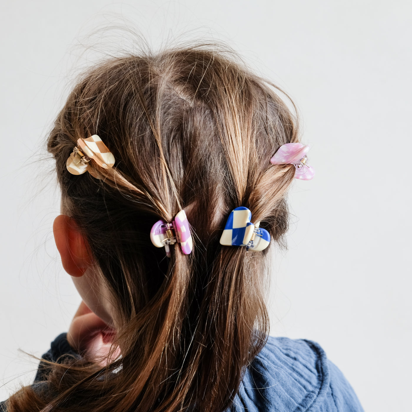 Heart shaped mini bulldog clips in brightly coloured patterns worn by little dark haired girl