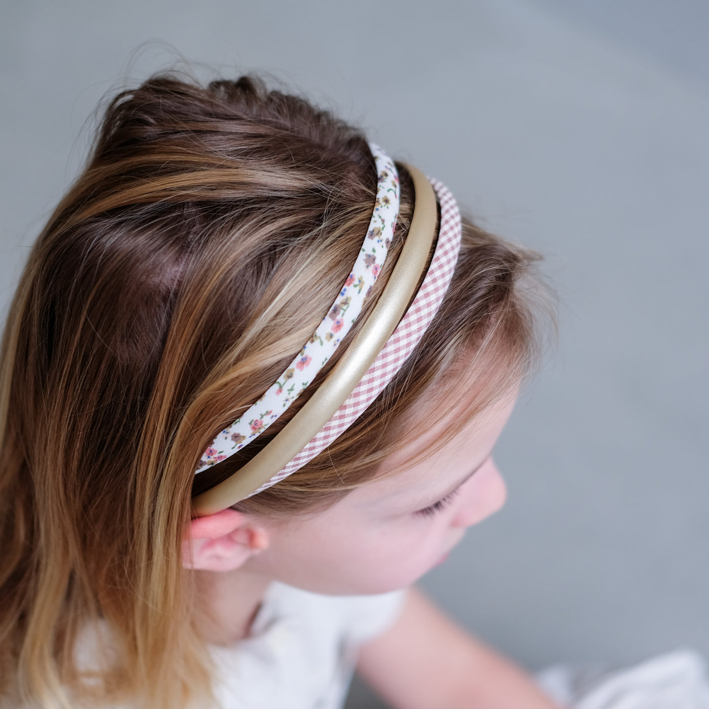Little girl wearing three Alice bands in gingham, floral ditsy and soft pink gingham fabrics