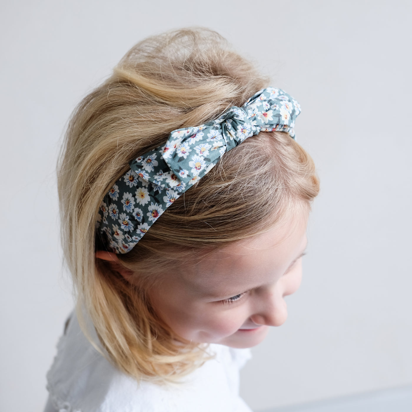 Little girl wearing daisy print floral Alice band with bow