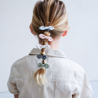 Cute floral and gingham fabric bow ponies worn in a low ponytail hairstyle by fine-haired little girl