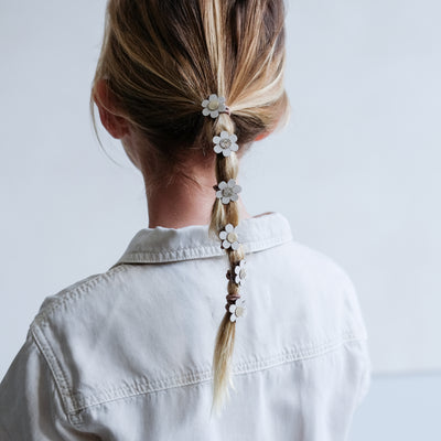 Little girl with fine hair, in a ponytail hairstyle, wearing daisy mini ponies featuring gold centres