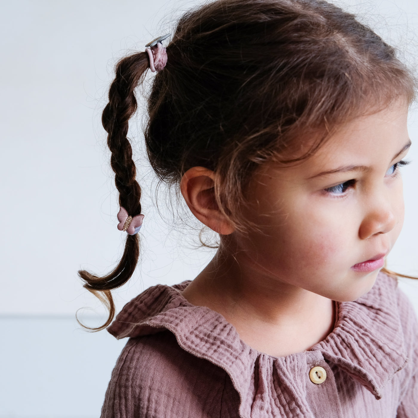 Soft metallic fabric winged butterfly pony with glitter body, worn by fine haired little girl in a high plaited pigtail hairstyle