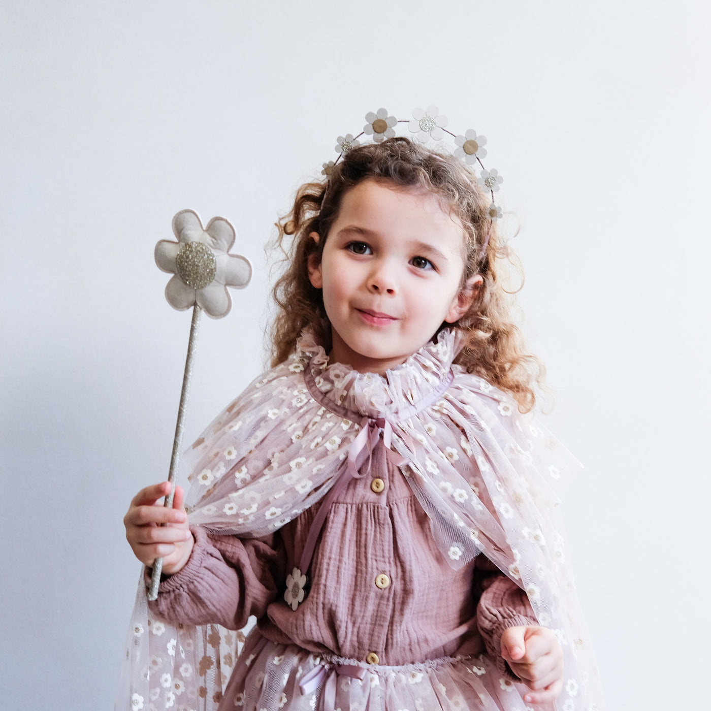 Little girl wearing a pretty daisy headband, holding a daisy wand