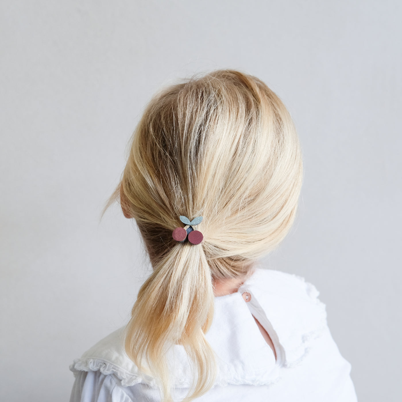 Little blonde haired girl wearing a sweet cherry pony elastic 