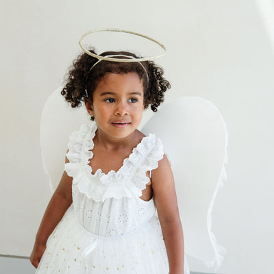 Dark haired little girl wearing a white tulle layered tutu, a gold halo headdress and a beautiful pair of angel wings