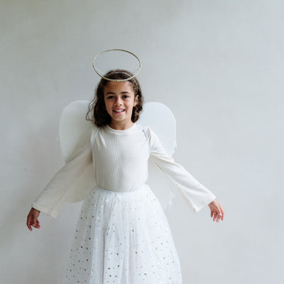 Dark haired little girl wearing a white tulle layered tutu, a gold halo headdress and a beautiful pair of angel wings