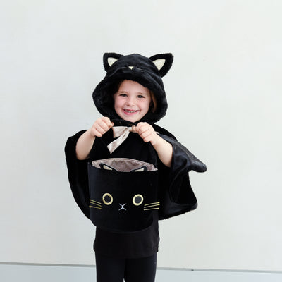 Little girl dressed up in a black fluffy cat cape with hood and satin bow tie holding a black cat face trick or treat bag