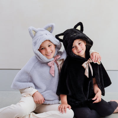Two little girls wearing fluffy dressing up cat costumes, one grey and one black