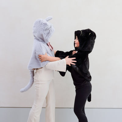 Two little girls wearing fluffy dressing up cat costumes, one grey and one black