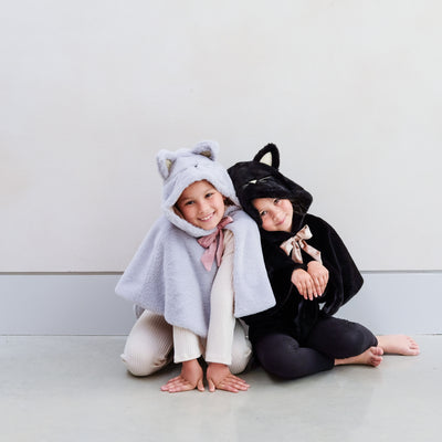 Two children playing wearing black and grey furry cat dressing up capes