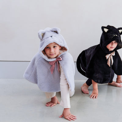 Two children playing wearing black and grey furry cat dressing up capes