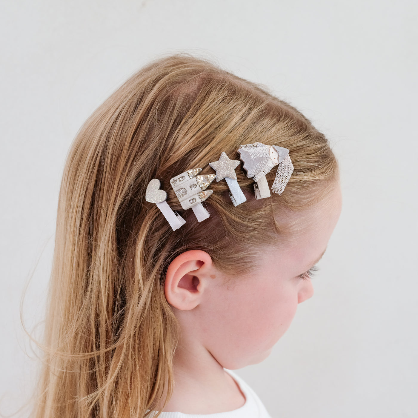 Four mini hair clips worn in dark blonde hair to the side - princess and castle theme with gold glitter