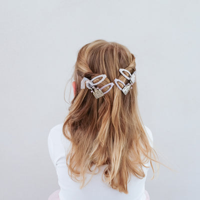 Part up hairdo on child secured with princess themed hair clips - two castes and two princesses with tulle and glitter details