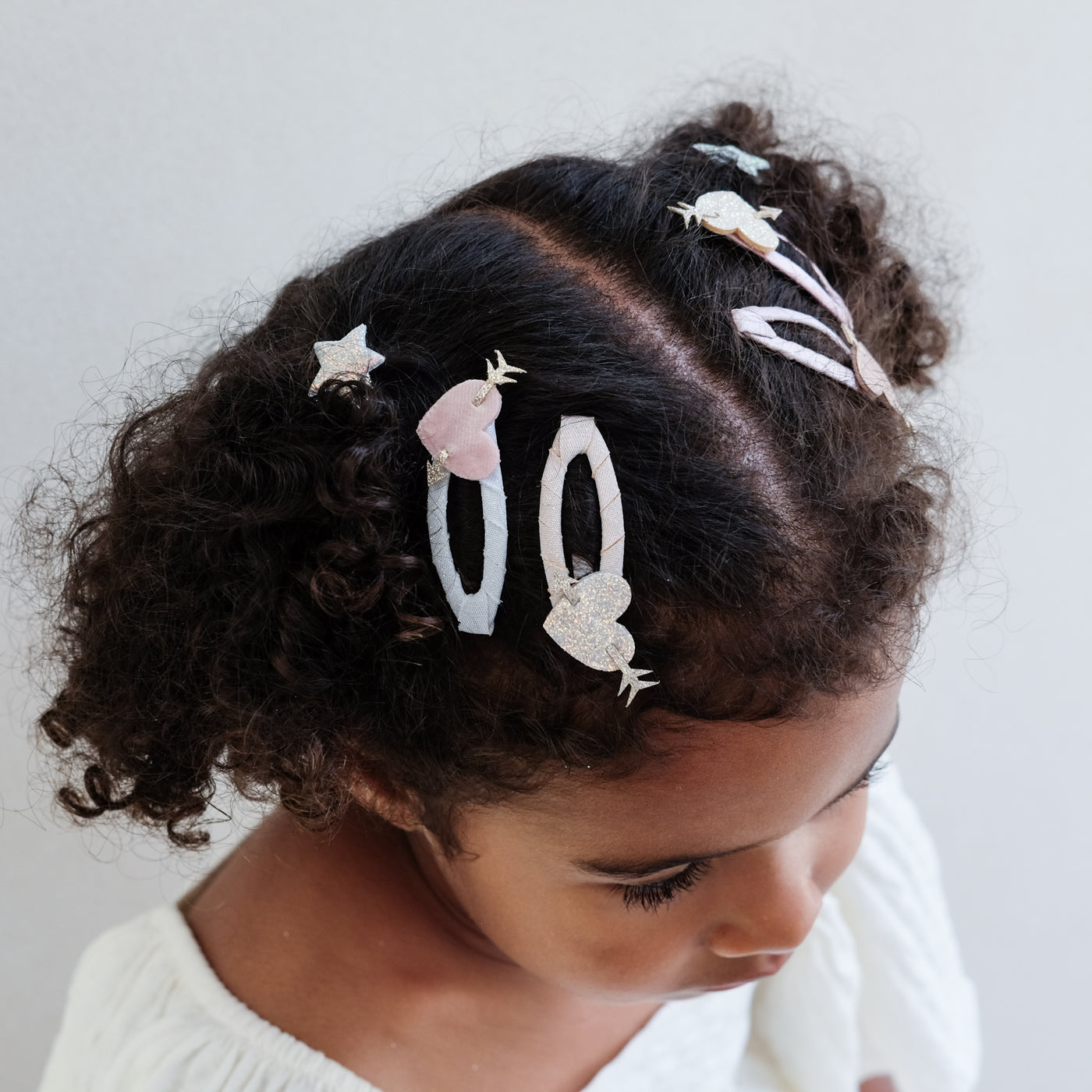 Dark haired girl wearing heart shaped hair clips with glitter arrows