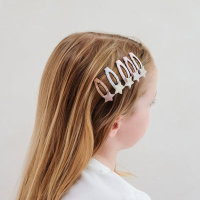Five pack of mini star hair clips worn to the side of young dark blonde child - glitter and metallic fabrics