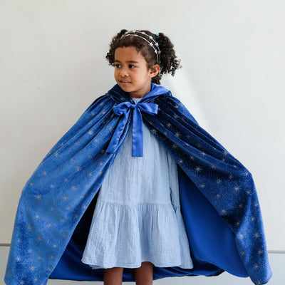 girl wearing an ice queen velvet cape against a white background