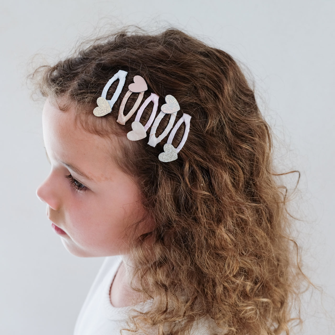 young girl wearing heart mini clic clacs in her hair against a white background