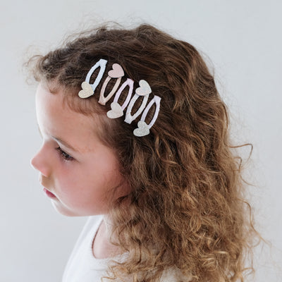 young girl wearing heart mini clic clacs in her hair against a white background