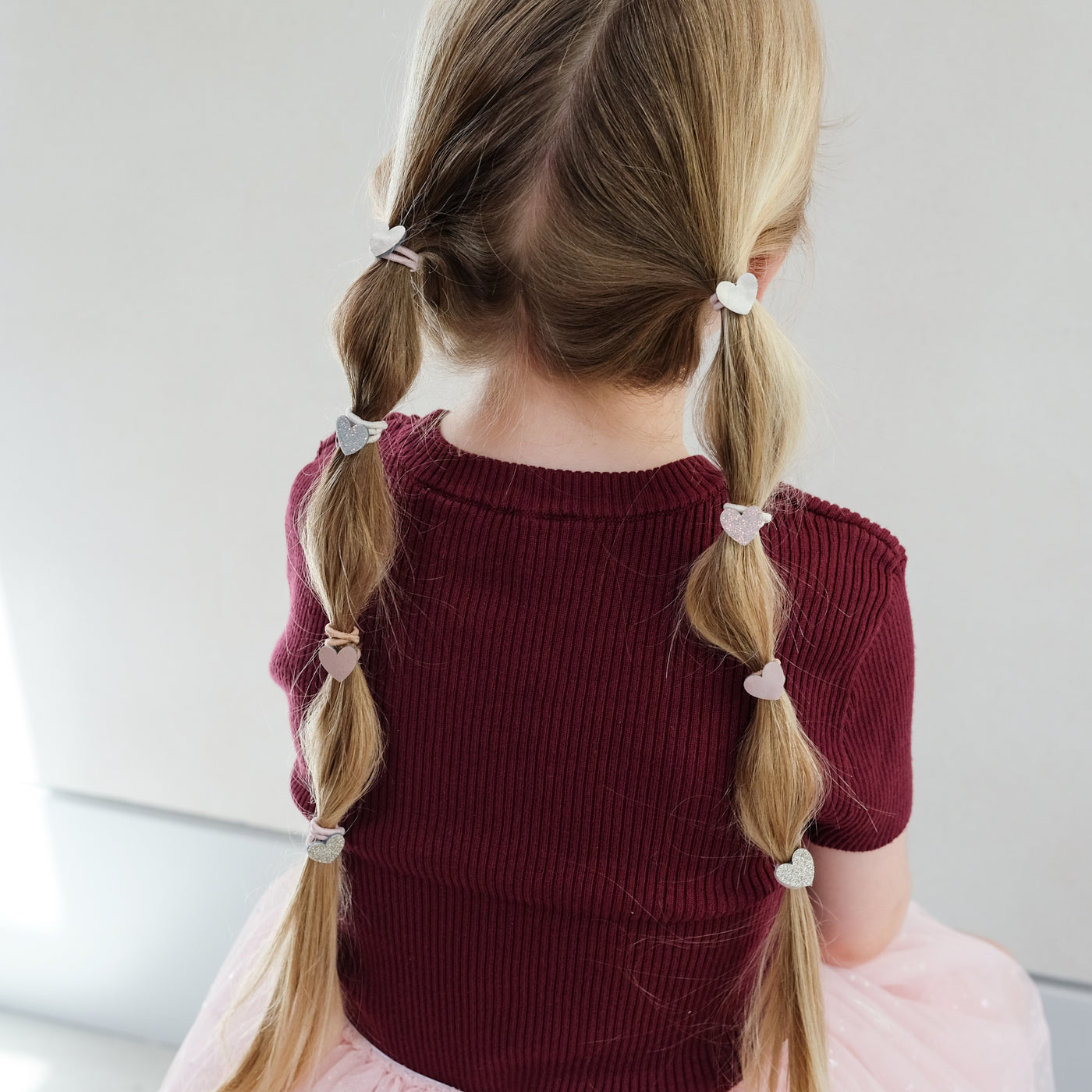girl wearing heart mini ponies in hair against white background