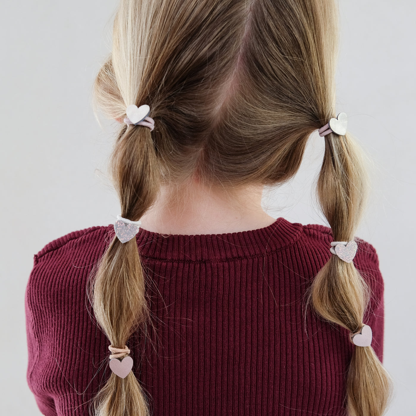 girl wearing heart mini ponies in hair against white background
