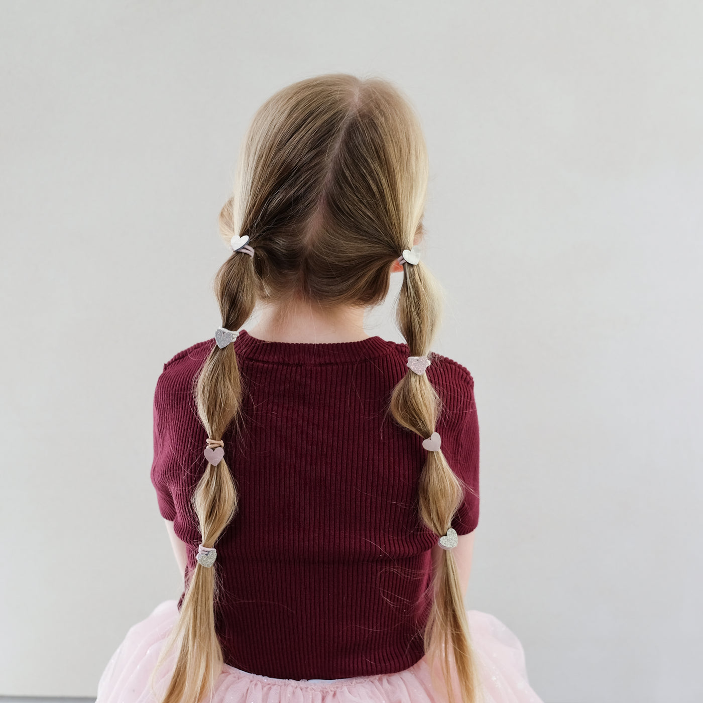 girl wearing heart mini ponies in hair against white background
