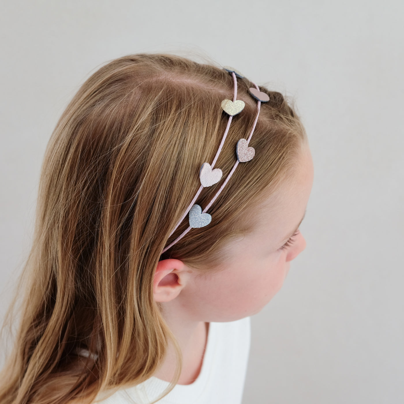 young girl wearing a heart double headband against a white background