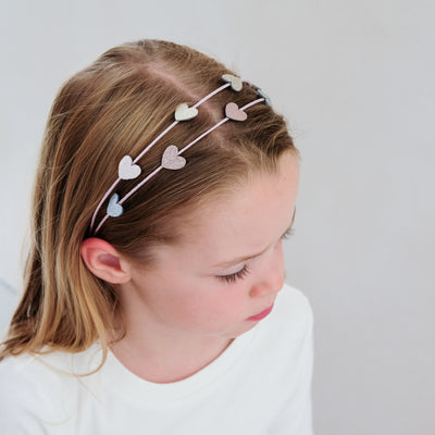 young girl wearing a heart double alice band against a white background