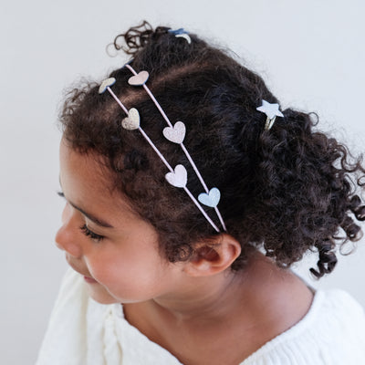 young girl wearing a heart double alice band against a white background