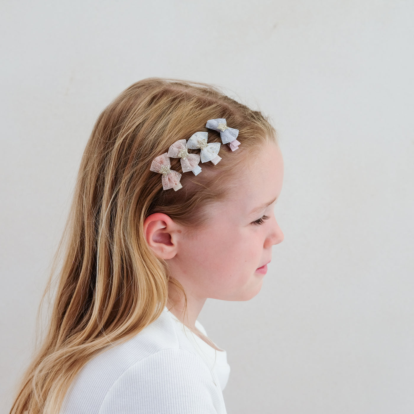 girl wearing tutu bow mini clips in her hair against a plain white background
