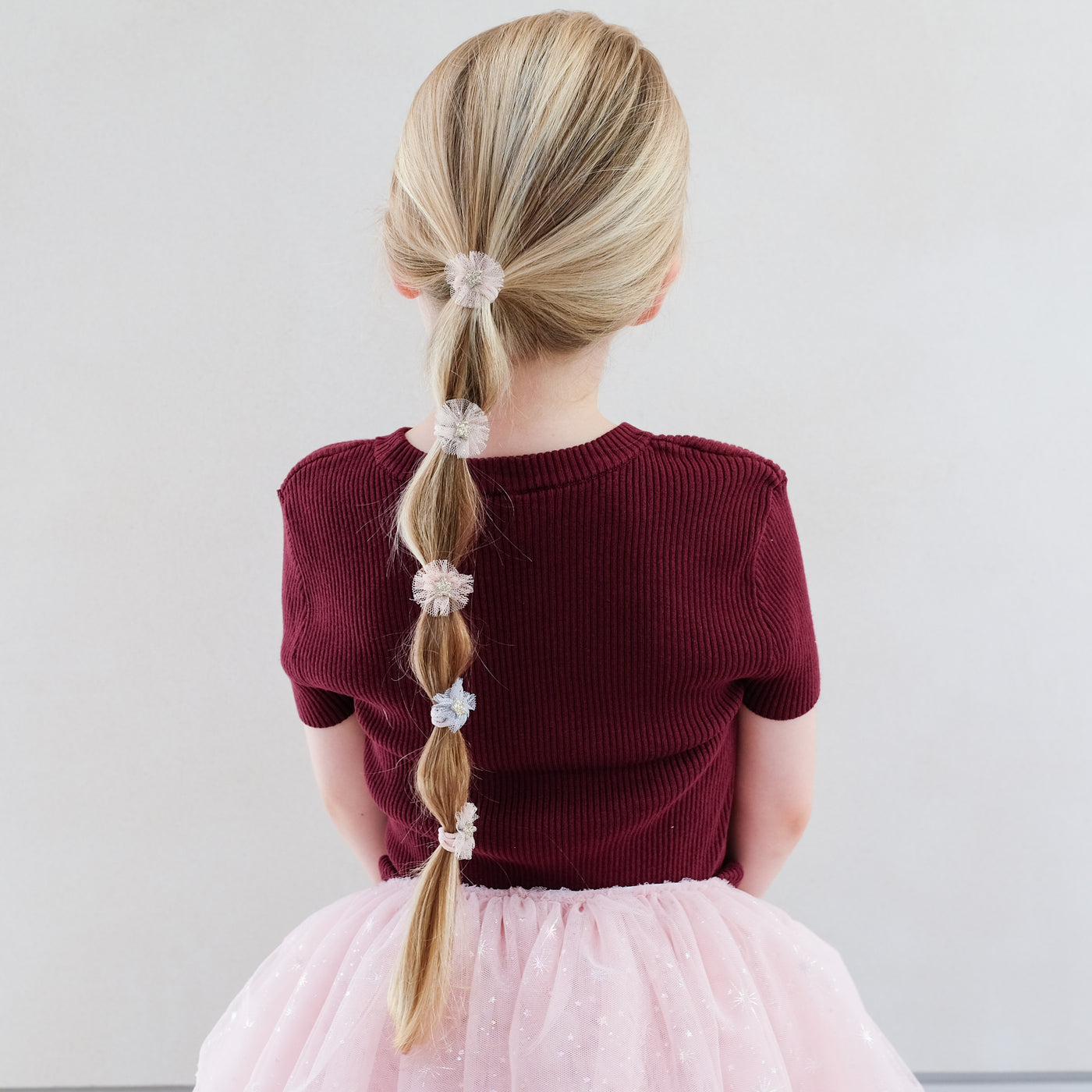 girl wearing Mini tulle rosette ponies in hair against white background