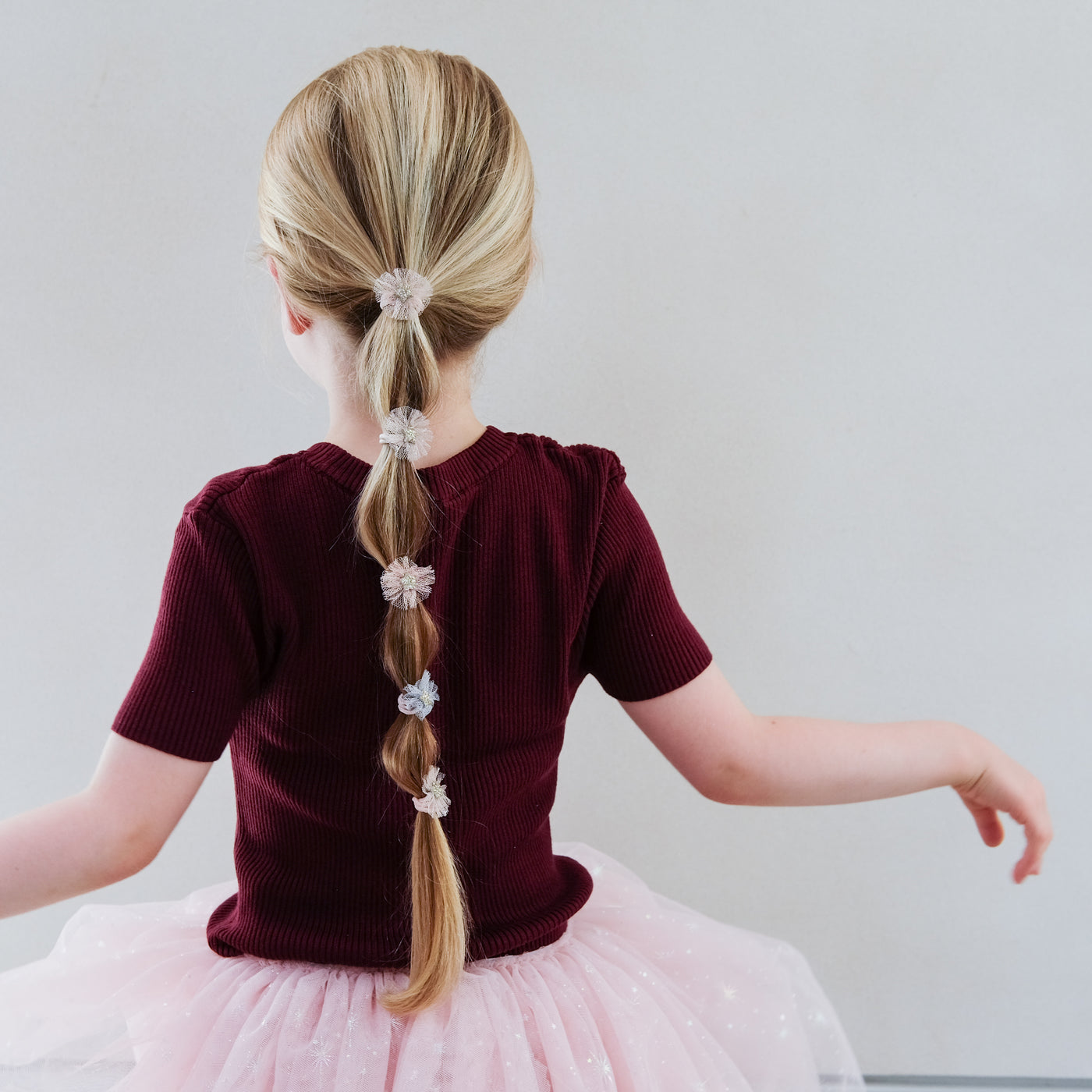 girl wearing Mini tulle rosette ponies in hair against white background