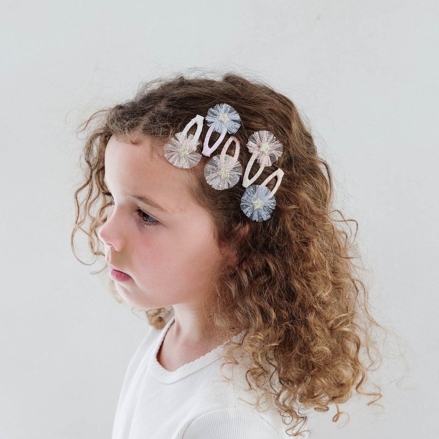girl wearing Mini tulle rosette clic clacs in her hair against a plain background