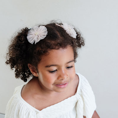 girl wearing ballerina star tulle hair clips in her hair against a white background