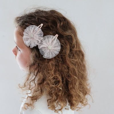girl wearing ballerina star tulle hair clips in her hair against a white background