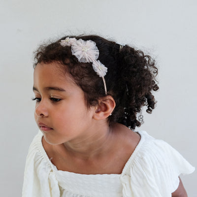 girl wearing a tulle star rosette alice band against a white background