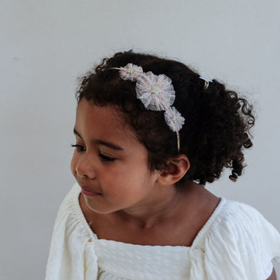 girl wearing a tulle star rosette alice band against a white background
