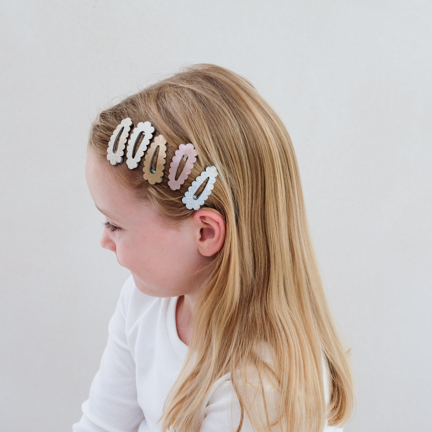 girl wearing scalloped mini clic clacs in her hair against a plain background
