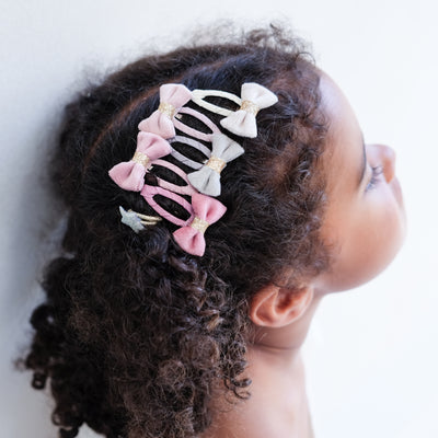 girl wearing Tinkerbell velvet bow mini clic clacs in her hair against a plain background
