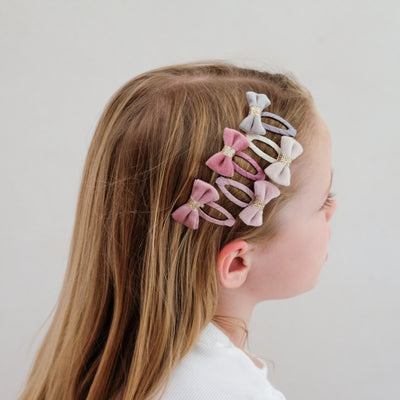 girl wearing Tinkerbell velvet bow mini clic clacs in her hair against a plain background