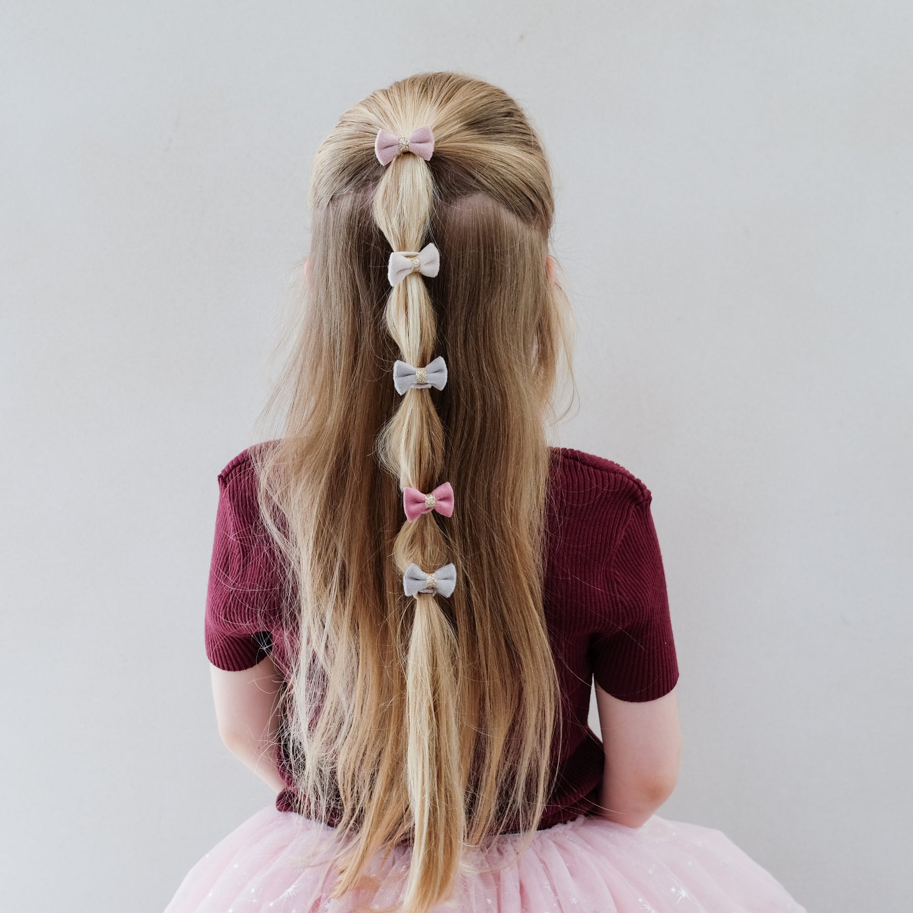 girl wearing tinkerbell mini velvet bow ponies in hair against a white background