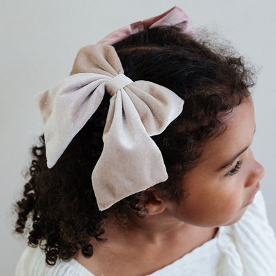 girl wearing velvet agnes oversized bow hair clip in her hair against a white background
