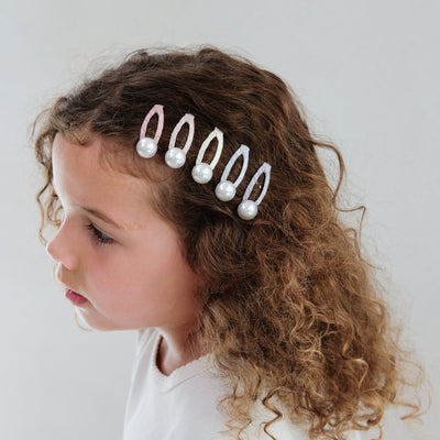 girl wearing pearly hair clips in her hair against a plain background